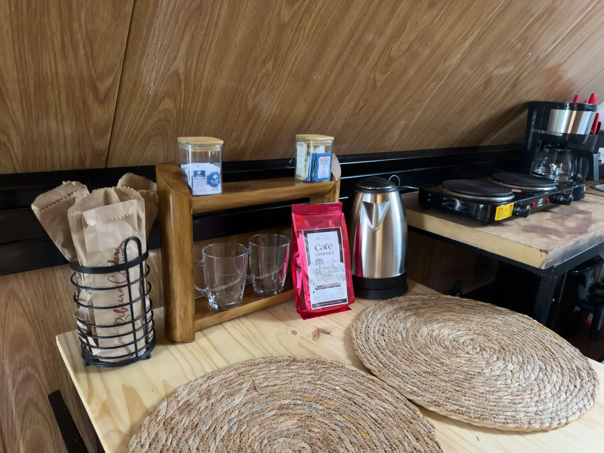 Cantinho do café com chaleira, cafeteira e café da casa