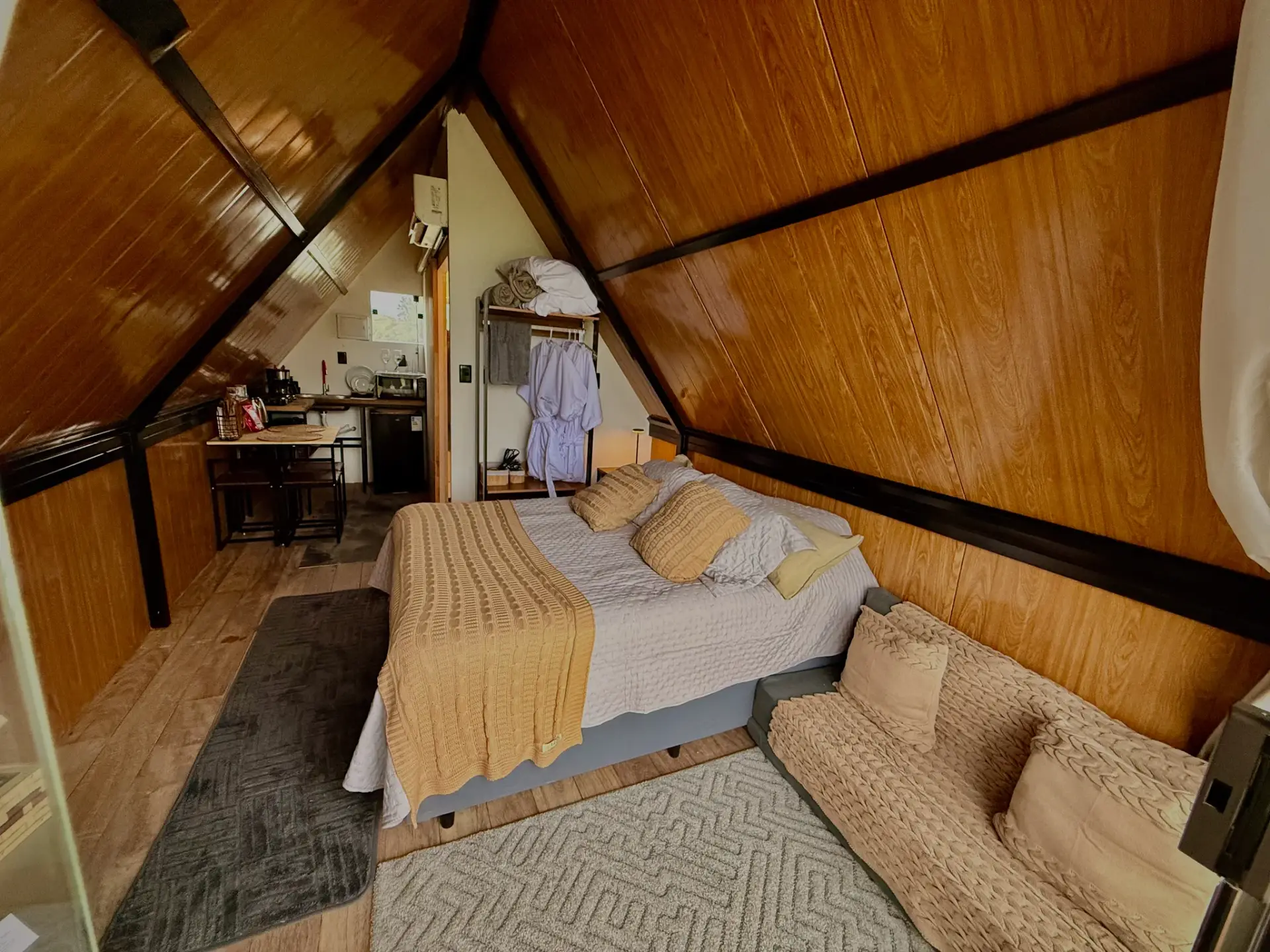 Quarto com arara de roupões e copa ao fundo